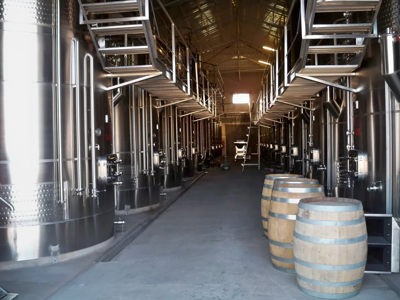 Interior de la bodega: piletas de acero inoxidable y barricas